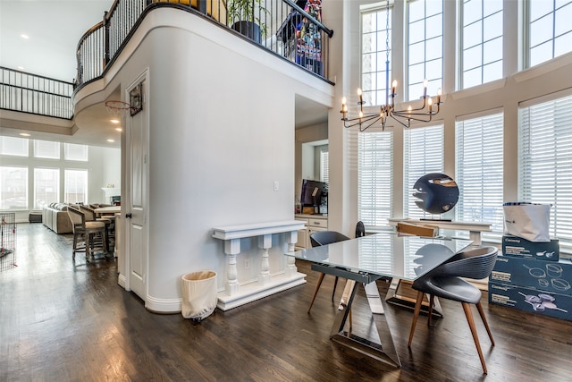 dining space with an inviting chandelier, wood-type flooring, and a towering ceiling