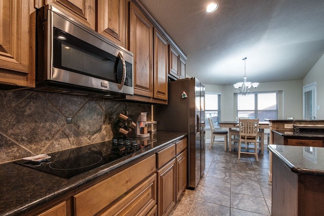 kitchen featuring stainless steel appliances, lofted ceiling, a notable chandelier, tasteful backsplash, and pendant lighting