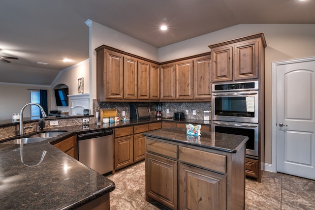 kitchen with sink, a center island, vaulted ceiling, and stainless steel appliances