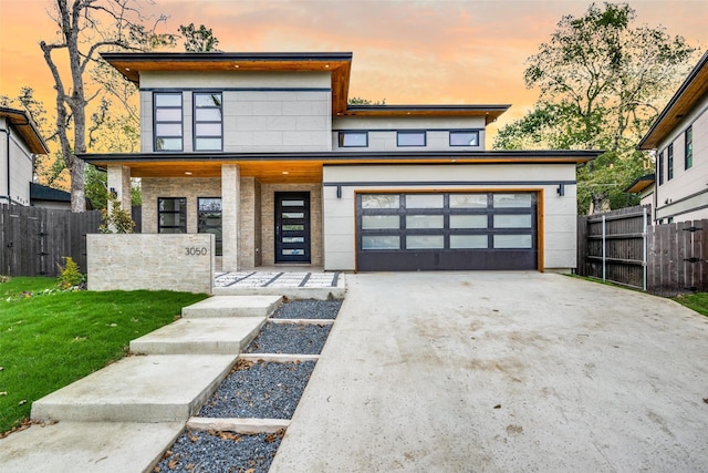 contemporary home featuring a garage, fence, and concrete driveway