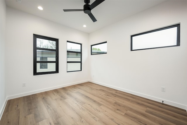 spare room with light wood-type flooring, a wealth of natural light, and ceiling fan