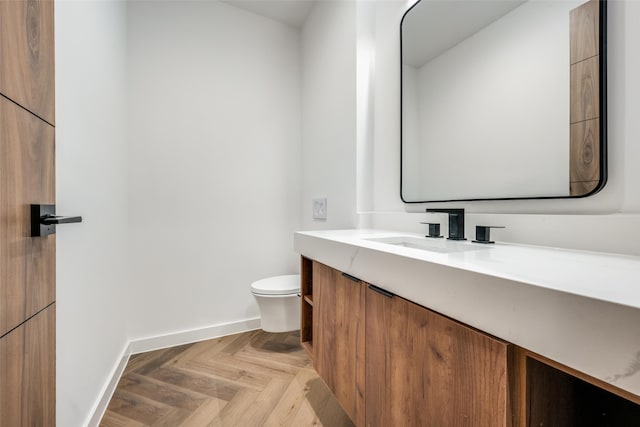 bathroom featuring vanity, toilet, and parquet flooring