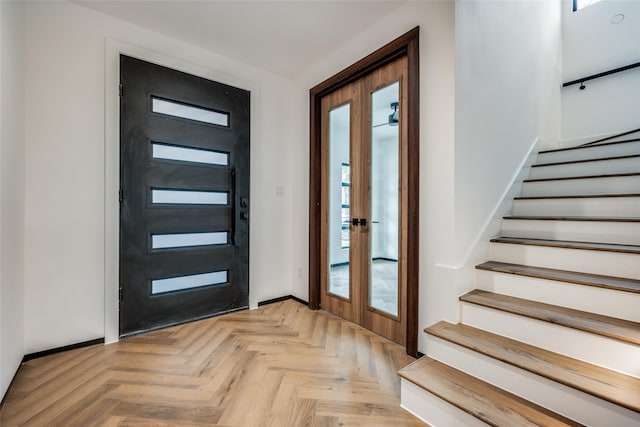 foyer entrance with french doors, light parquet flooring, and a healthy amount of sunlight