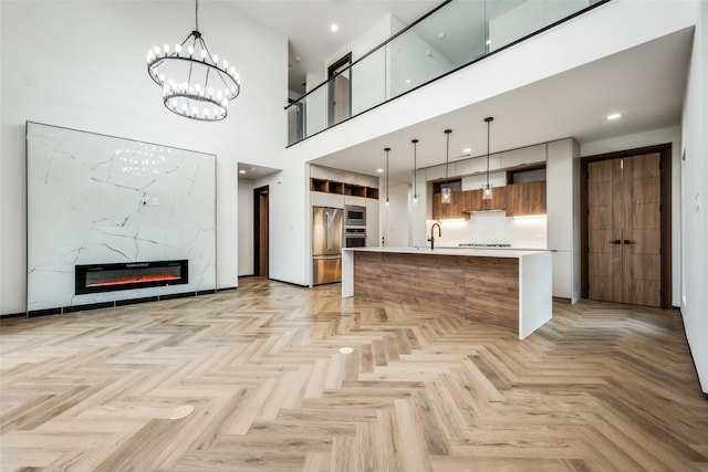 kitchen featuring pendant lighting, a premium fireplace, appliances with stainless steel finishes, and light parquet floors