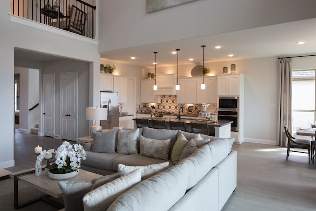 living room with light hardwood / wood-style floors and a towering ceiling