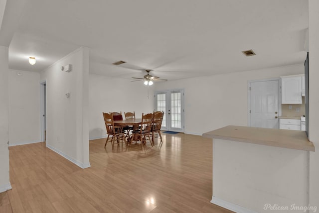 dining room featuring ceiling fan, light wood-type flooring, and french doors