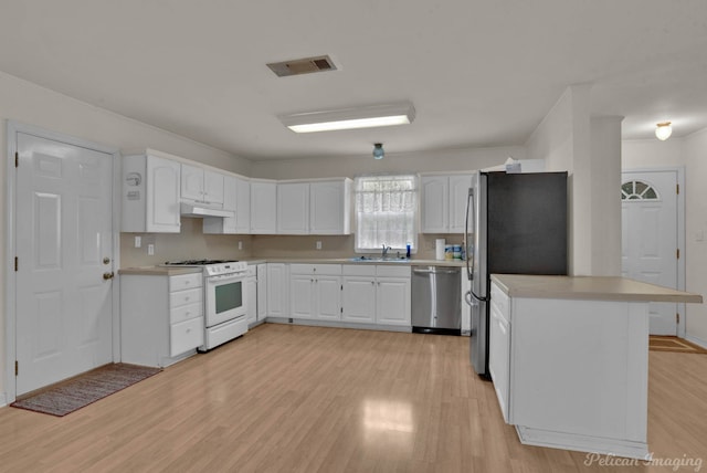 kitchen with stainless steel appliances, white cabinets, sink, and light hardwood / wood-style flooring