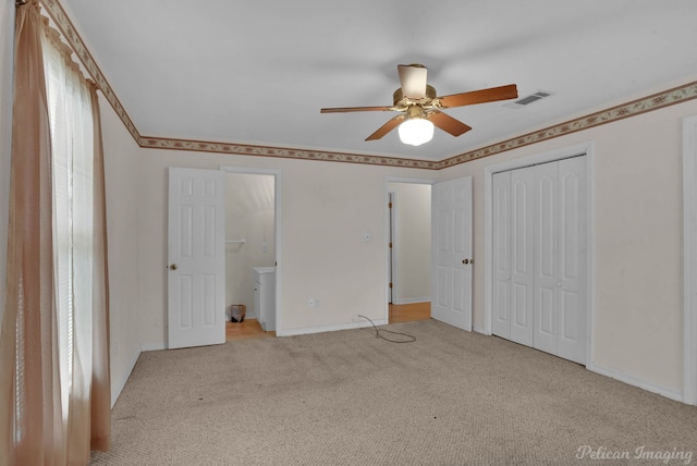 unfurnished bedroom with ensuite bathroom, multiple windows, light carpet, and ceiling fan