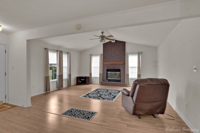 living room with light hardwood / wood-style floors, ceiling fan, a fireplace, vaulted ceiling with beams, and crown molding