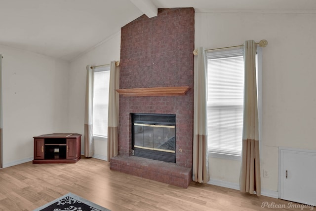 unfurnished living room featuring light wood-type flooring, vaulted ceiling with beams, a healthy amount of sunlight, and a fireplace