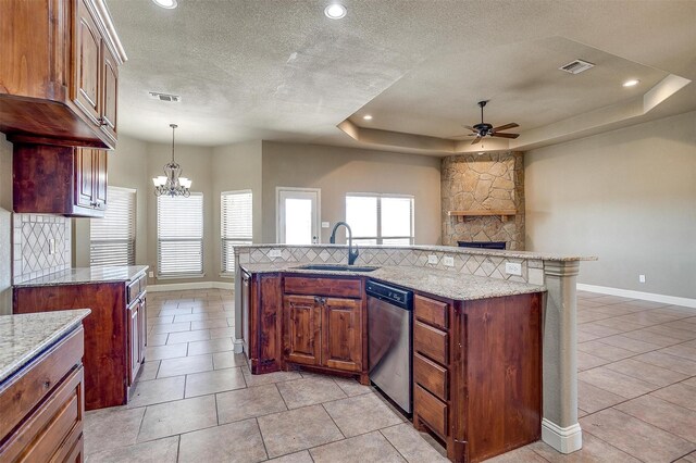 kitchen featuring backsplash, a stone fireplace, sink, stainless steel dishwasher, and a tray ceiling