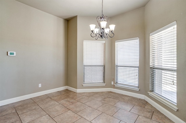 tiled spare room featuring a chandelier