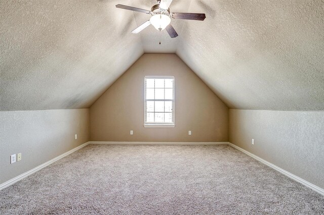 additional living space with a textured ceiling, carpet floors, vaulted ceiling, and ceiling fan