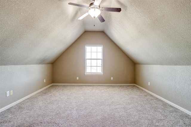 bonus room featuring ceiling fan, lofted ceiling, carpet flooring, and a textured ceiling