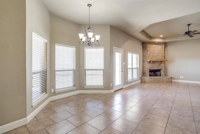 unfurnished living room with a tray ceiling, light tile patterned floors, ceiling fan with notable chandelier, and a fireplace