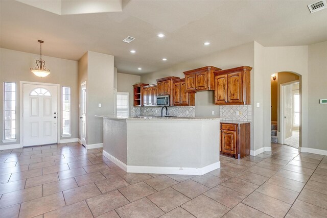 kitchen with pendant lighting, sink, light stone countertops, light tile patterned flooring, and decorative backsplash