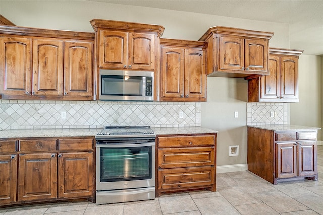 kitchen with light tile patterned floors, light stone countertops, backsplash, and appliances with stainless steel finishes