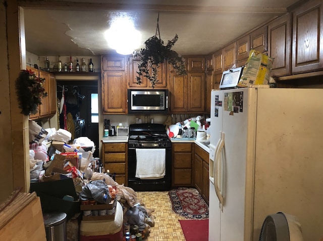 kitchen with black gas range oven and white refrigerator with ice dispenser