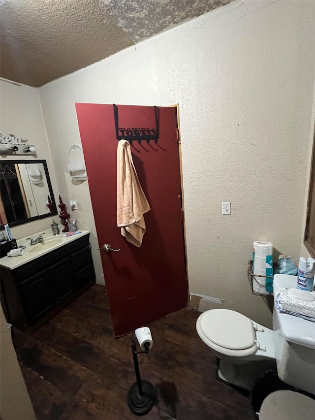 bathroom with vanity, toilet, wood-type flooring, and a textured ceiling