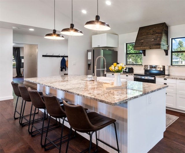 kitchen featuring white cabinets, stainless steel appliances, a large island with sink, and custom exhaust hood