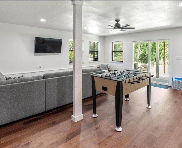 recreation room featuring hardwood / wood-style flooring, ceiling fan, and a textured ceiling