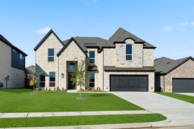 french country home featuring a front lawn and a garage