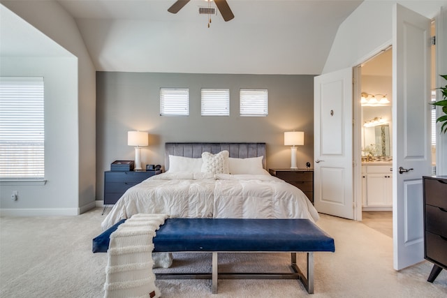 carpeted bedroom with ensuite bathroom, ceiling fan, multiple windows, and vaulted ceiling