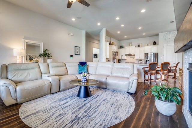 living room featuring dark wood-type flooring, ceiling fan, and sink