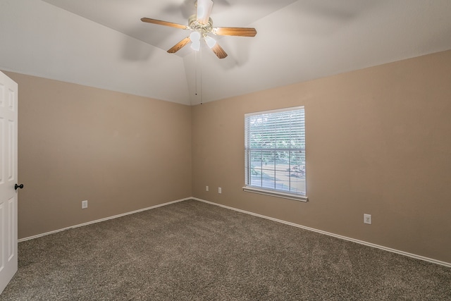 empty room featuring lofted ceiling, dark colored carpet, and ceiling fan