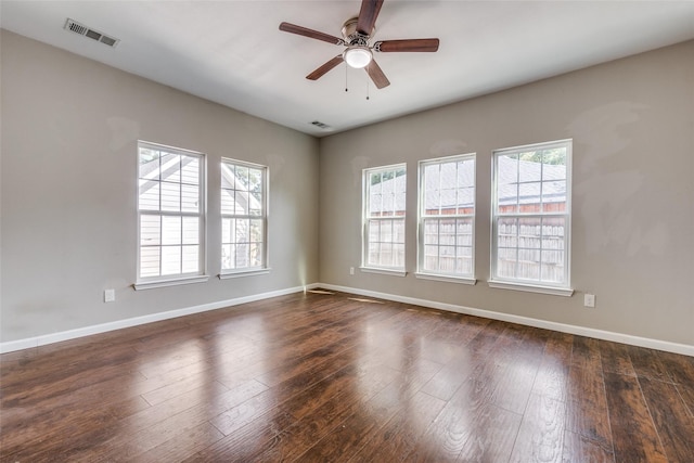 empty room featuring dark wood-type flooring, ceiling fan, and a healthy amount of sunlight