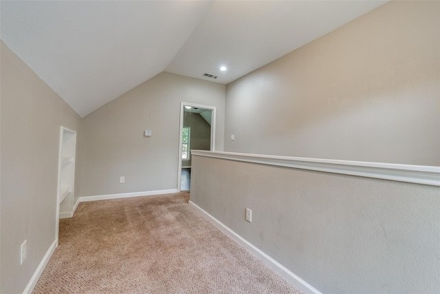 carpeted spare room featuring vaulted ceiling