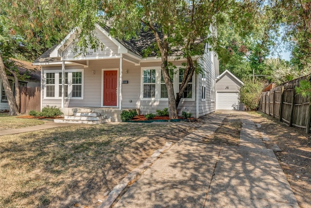 bungalow-style house with a garage, a front yard, and an outbuilding