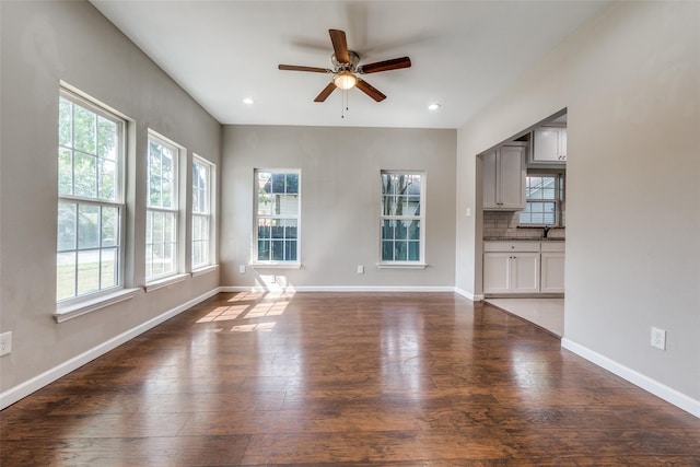 unfurnished living room with dark hardwood / wood-style flooring, ceiling fan, and sink