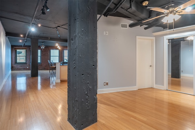 interior space featuring ceiling fan, wood-type flooring, and brick wall