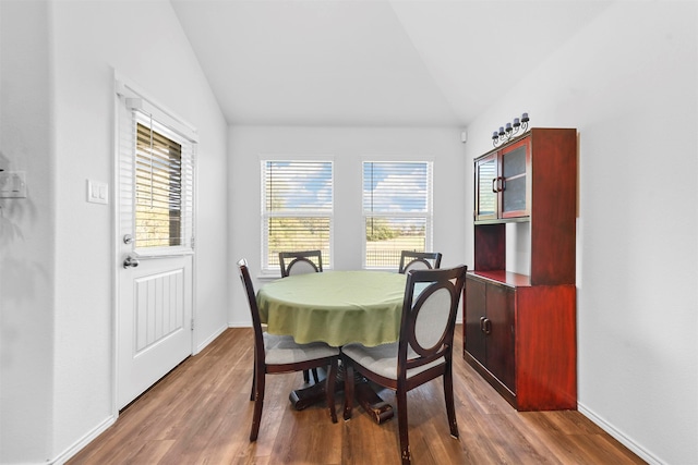 dining room with a healthy amount of sunlight, wood-type flooring, and lofted ceiling