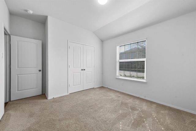 unfurnished bedroom featuring light colored carpet, vaulted ceiling, and a closet