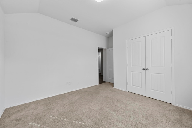 unfurnished bedroom featuring light carpet, a closet, and lofted ceiling