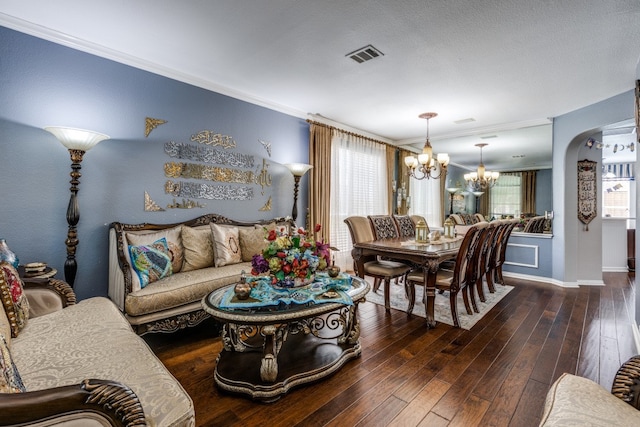 living room with dark wood-type flooring, a notable chandelier, and ornamental molding