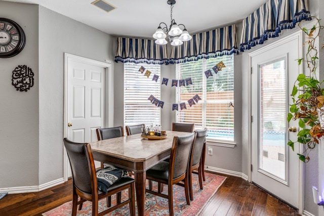 dining room with dark hardwood / wood-style flooring and a chandelier