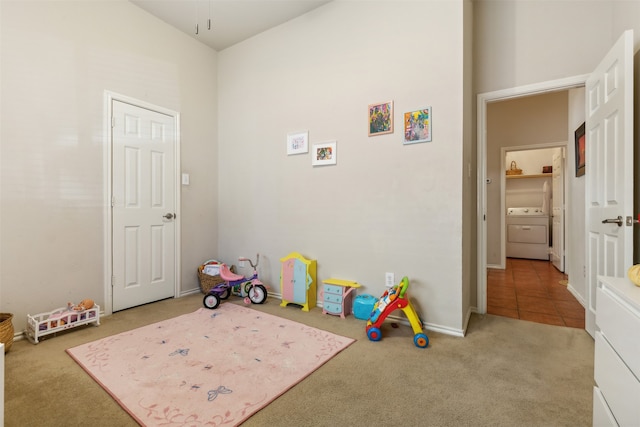 rec room with a high ceiling, light colored carpet, and washer / dryer