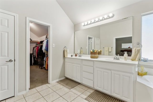 bathroom with lofted ceiling, a healthy amount of sunlight, tile patterned floors, and vanity