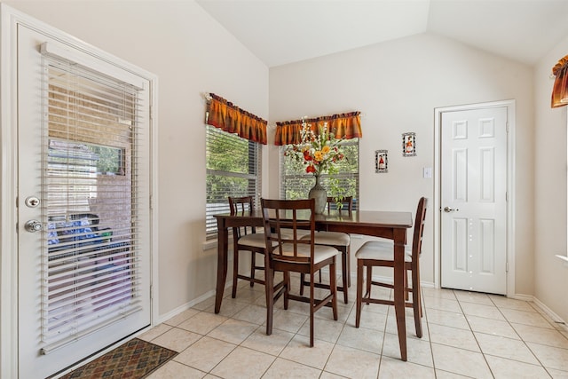 tiled dining room with a healthy amount of sunlight and vaulted ceiling