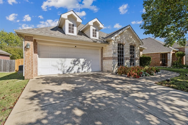 view of front of property featuring a front lawn, central air condition unit, and a garage