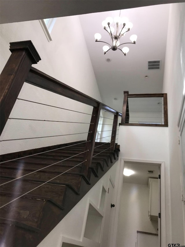 stairway featuring a towering ceiling, hardwood / wood-style floors, and an inviting chandelier