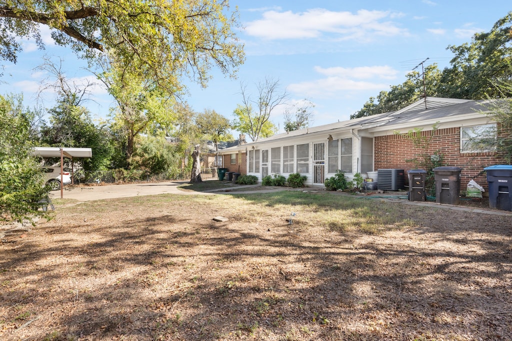 view of yard with central AC unit and a sunroom