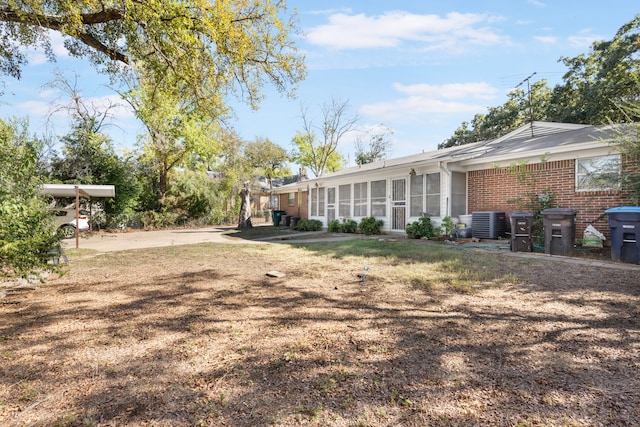 view of yard featuring central AC unit and a sunroom