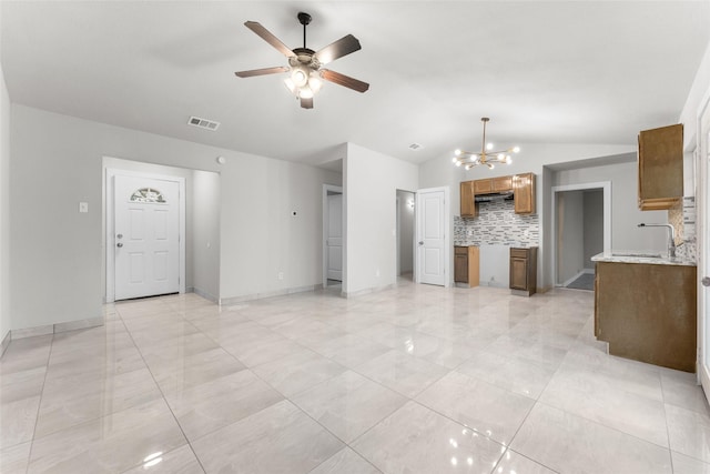 unfurnished living room featuring sink, vaulted ceiling, and ceiling fan with notable chandelier