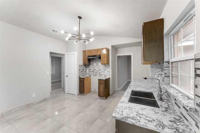 kitchen with decorative backsplash, sink, hanging light fixtures, a notable chandelier, and vaulted ceiling