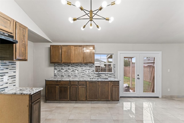 kitchen featuring vaulted ceiling, french doors, sink, tasteful backsplash, and a chandelier