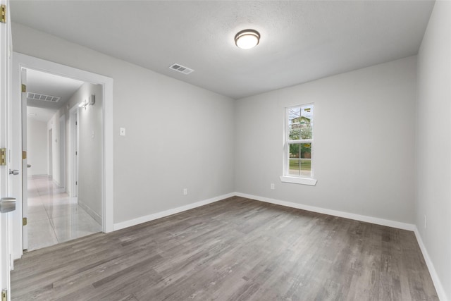 spare room featuring a textured ceiling and light hardwood / wood-style flooring